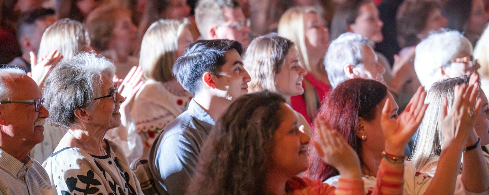 Un público de todas las edades aplaude en un auditorio
